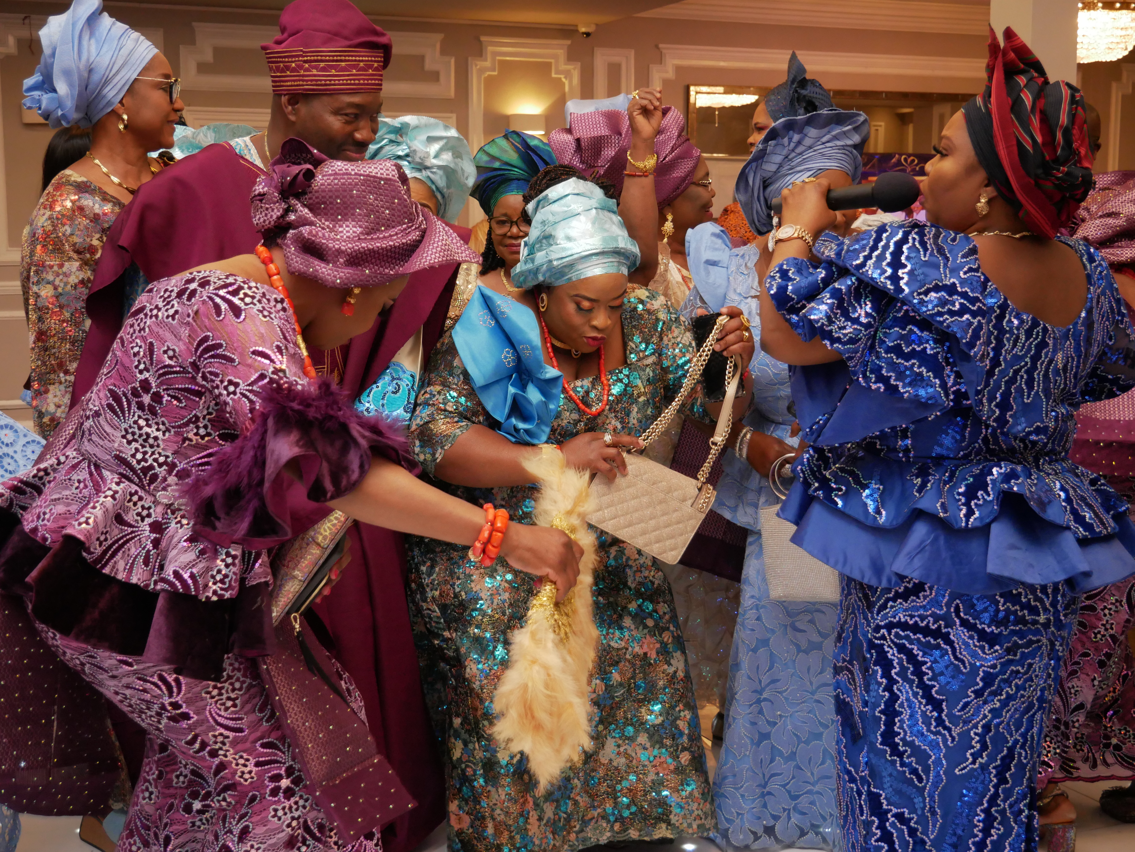 Family of the groom greeting the bride's family the Nigerian way at a traditional wedding in London. MC holding microphone to accept their greetings