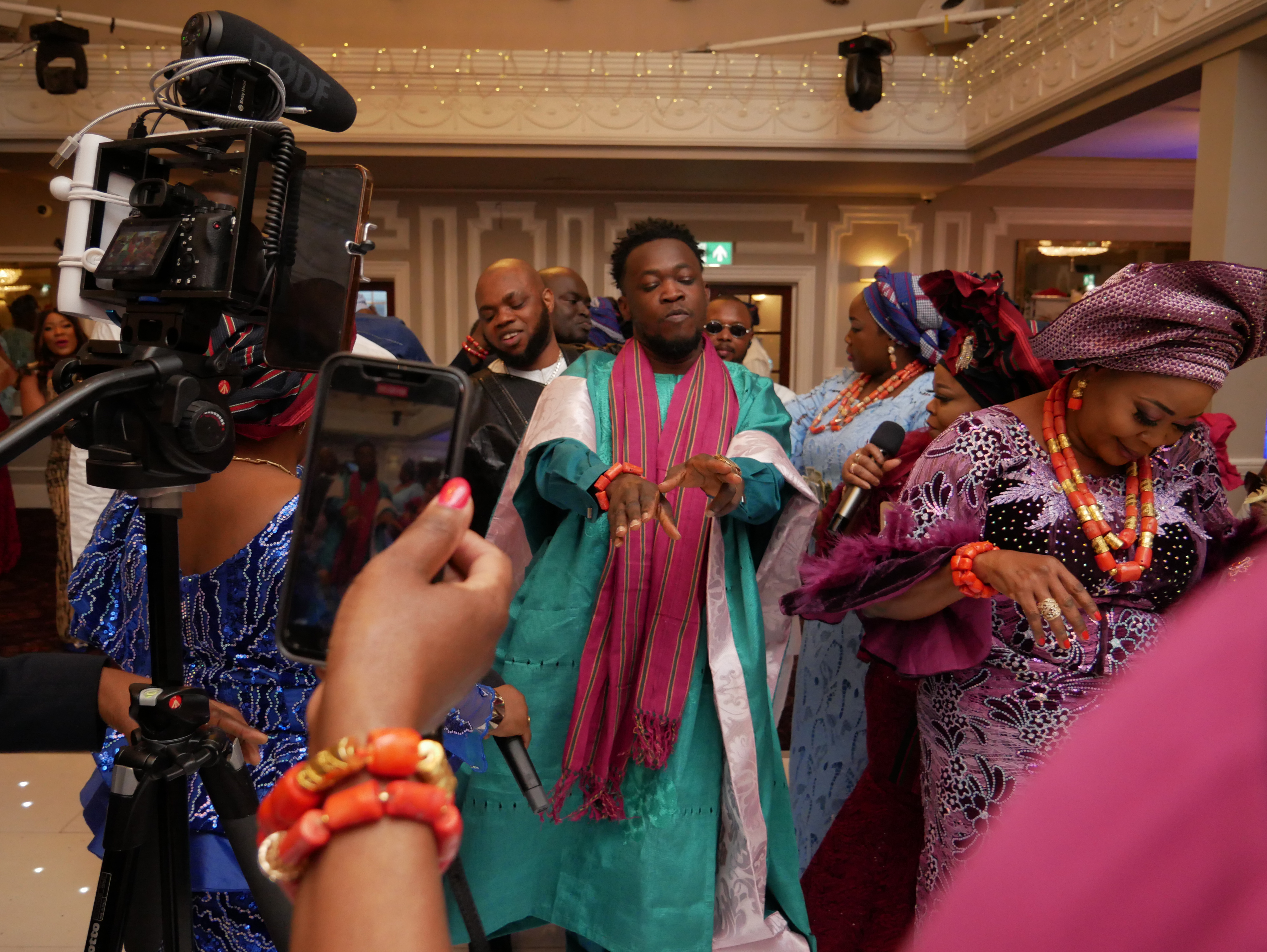 Groom and mum showing their Dance Moves at a Nigerian Traditional Wedding. Guest holding phone and professional cameraman both recording this event