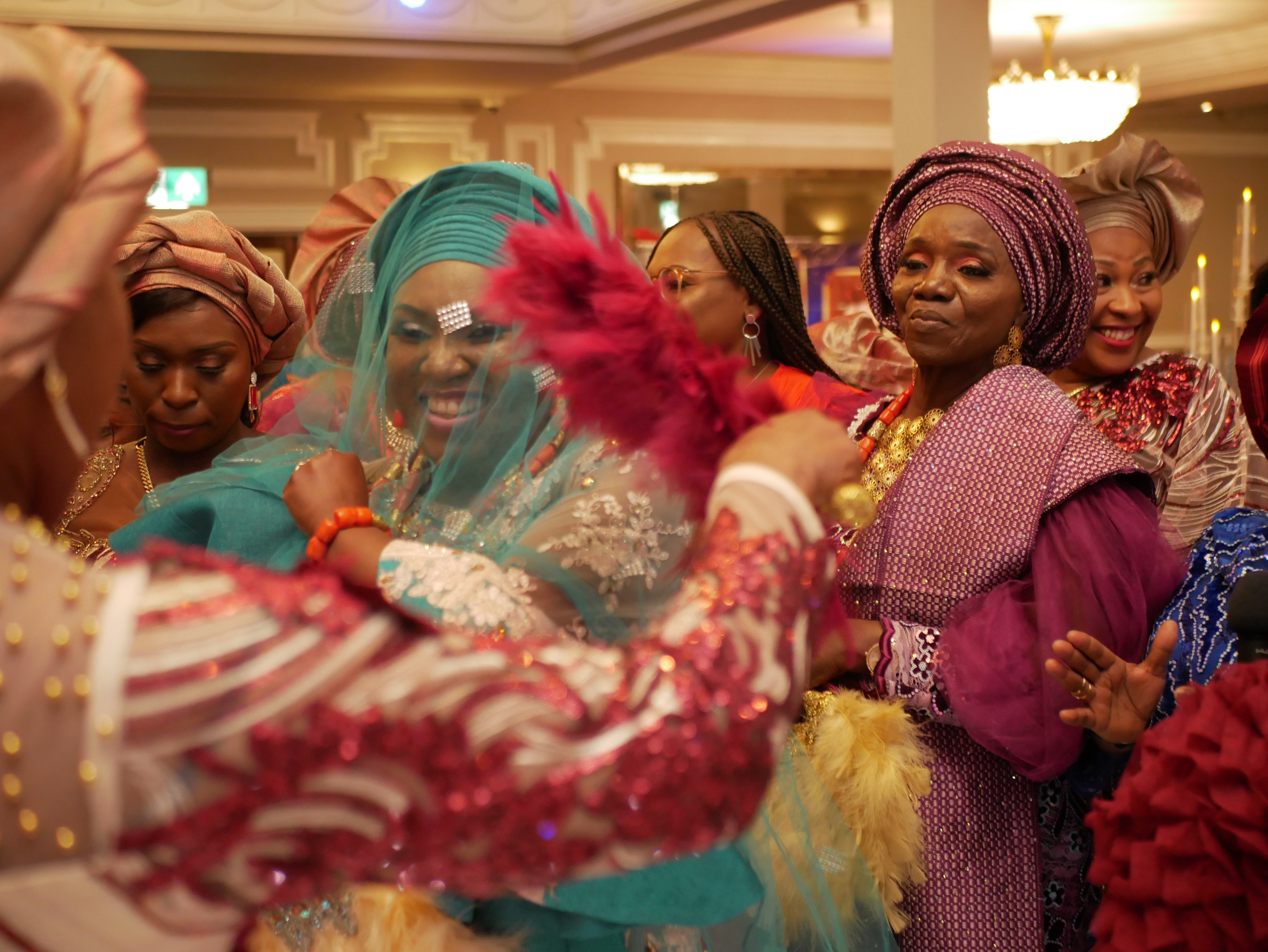 Bride and her mum with family members dancing on the dancefloor in full Nigerian traditional outfit and headgear