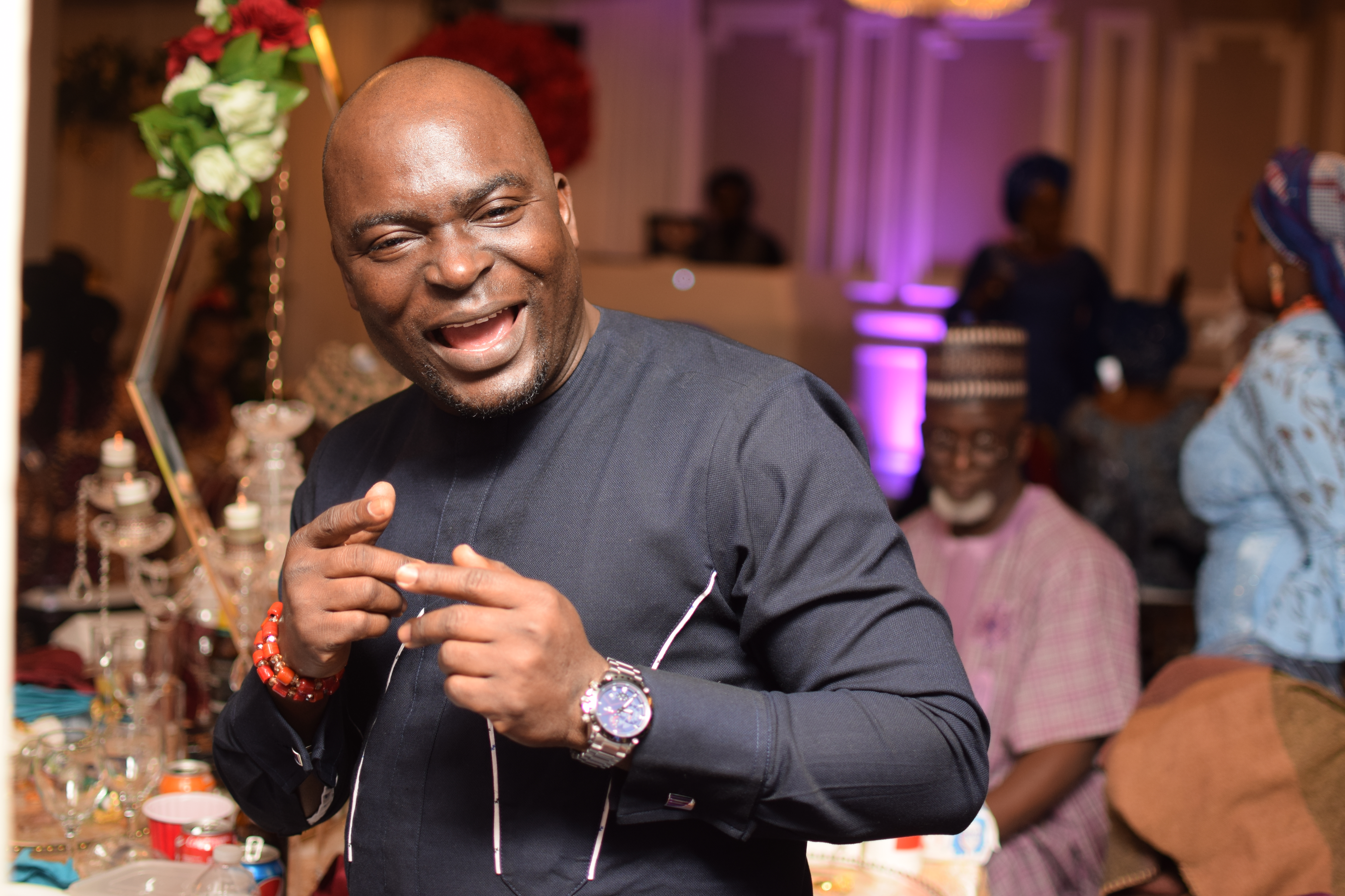 Guest with a big smile on his face wearing a blue african traditional outfit at a Nigerian wedding in Prince regent hotel London
